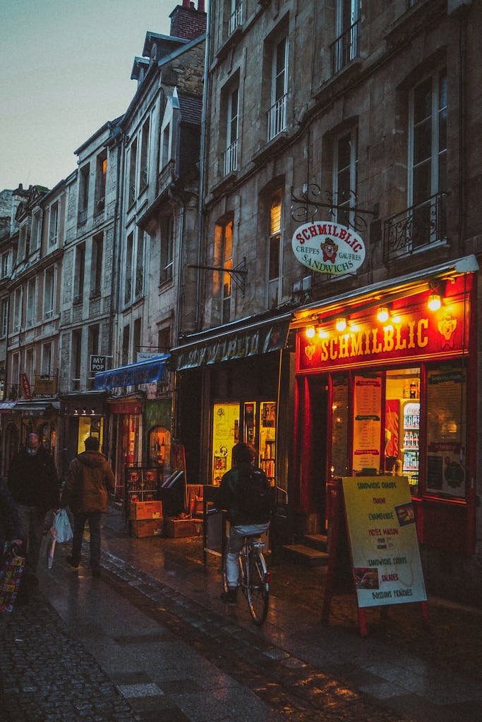 Explore a cozy evening street scene in Caen, Normandy, with warm lights and local charm.
