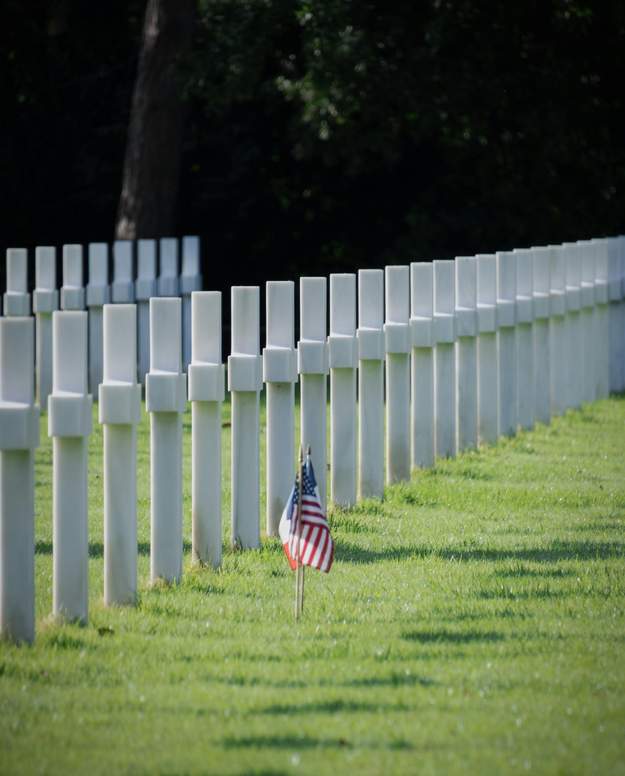 Flags adorn graves at the serene American Cemetery in Normandy, honoring fallen heroes.