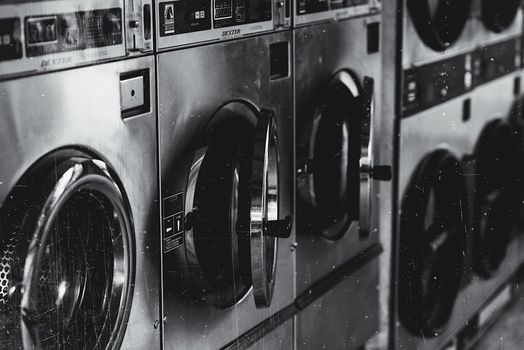 Black and white image of industrial washing machines in a retro style laundry facility.