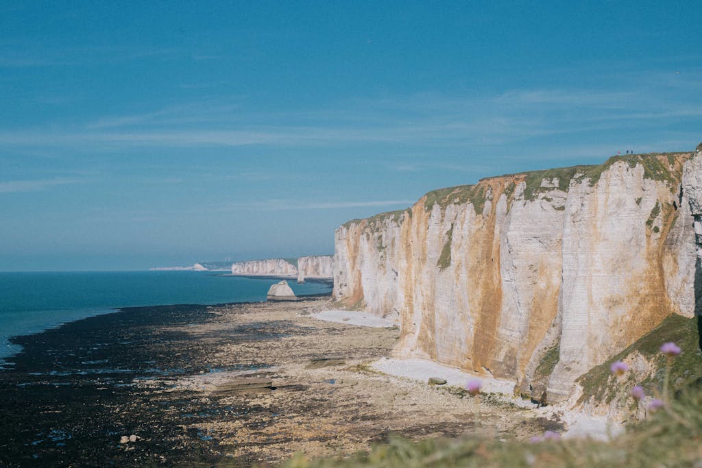 Breathtaking view of the majestic cliffs at Étretat, Normandie, France, with clear blue skies and tranquil sea.