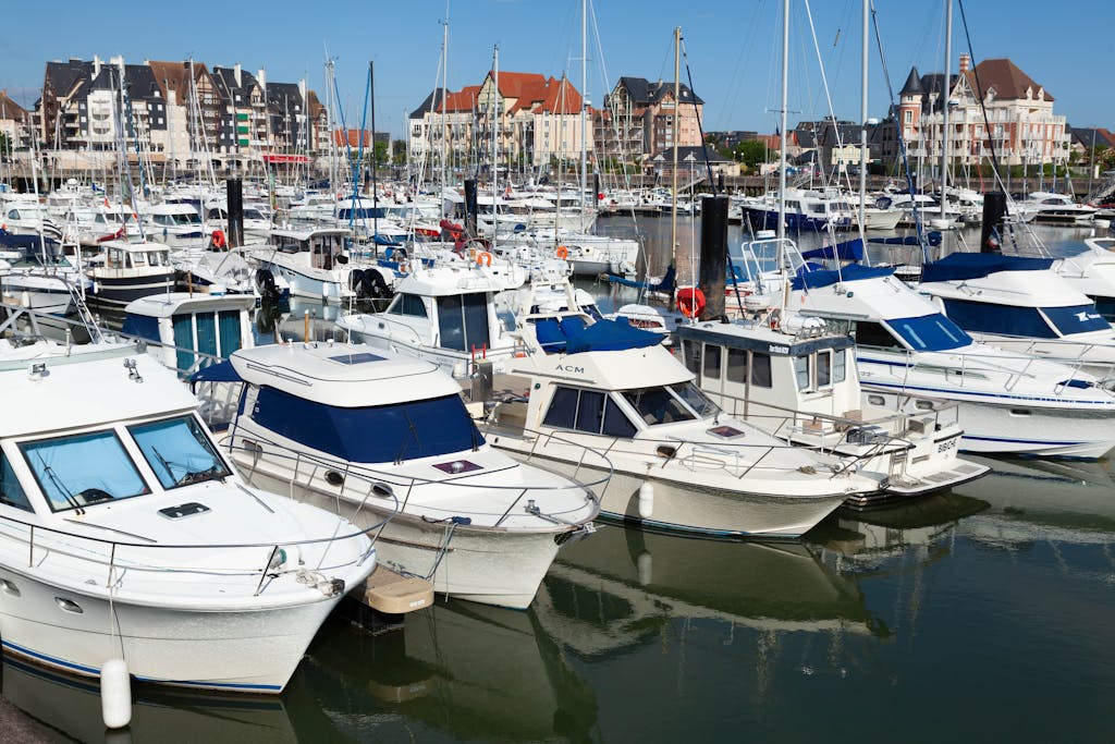Picturesque view of a bustling harbor in Dives-sur-Mer, Normandy with yachts and architectural backdrop.