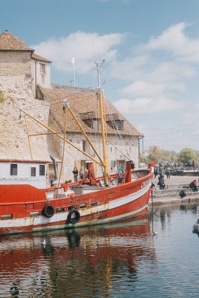 Red fishing boat docked at picturesque Honfleur harbor, capturing historic Normandy charm.